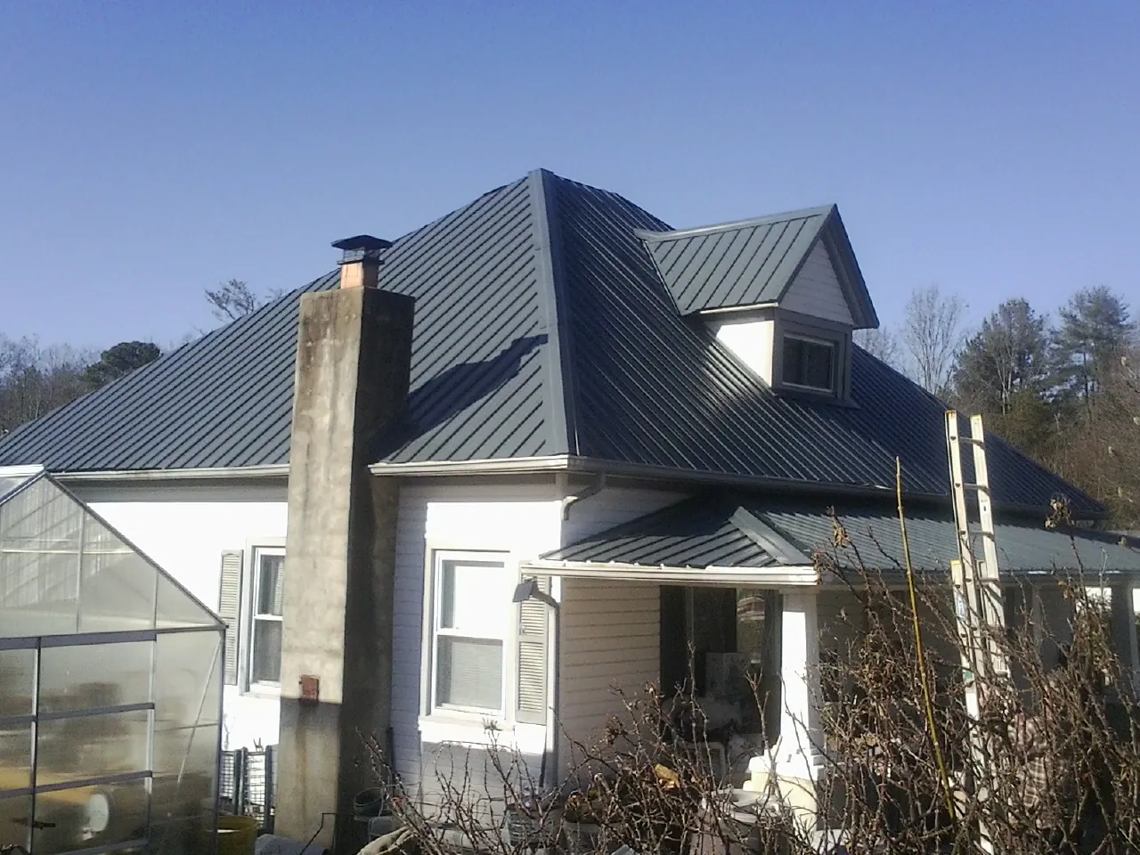 Dark blue standing seam metal roof on a white farmhouse with dormer — Slate & Tile Roof Repair by Roofing Brothers in Douglas City
