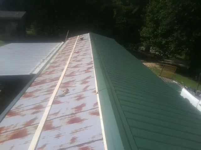 Old rusted panels beside newly installed green metal roofing — Wind Damage Roof Repair by Roofing Brothers in Douglas City