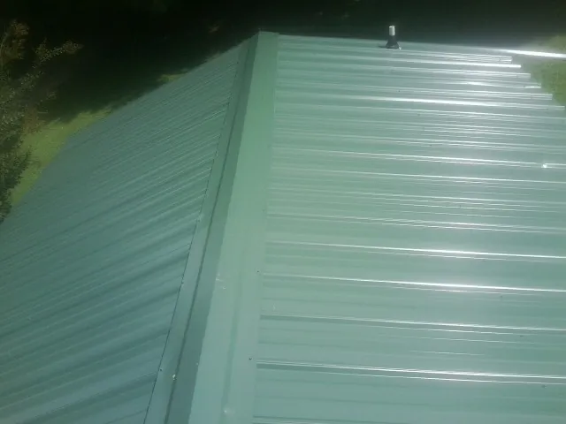 New green metal panels meeting at the ridge of a roof — Flat Roof Repair work by our crew in Douglas City