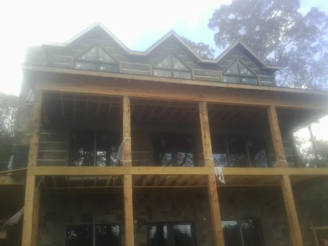 Dormers and porch framing on a large log home under construction — Roof Coating work by our crew in Douglas City