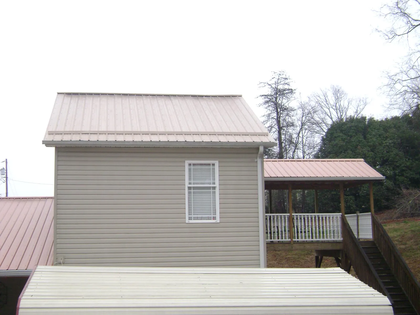 Tan metal roofs on a two story addition and attached porch, from a Roof Replacement job in Douglas City