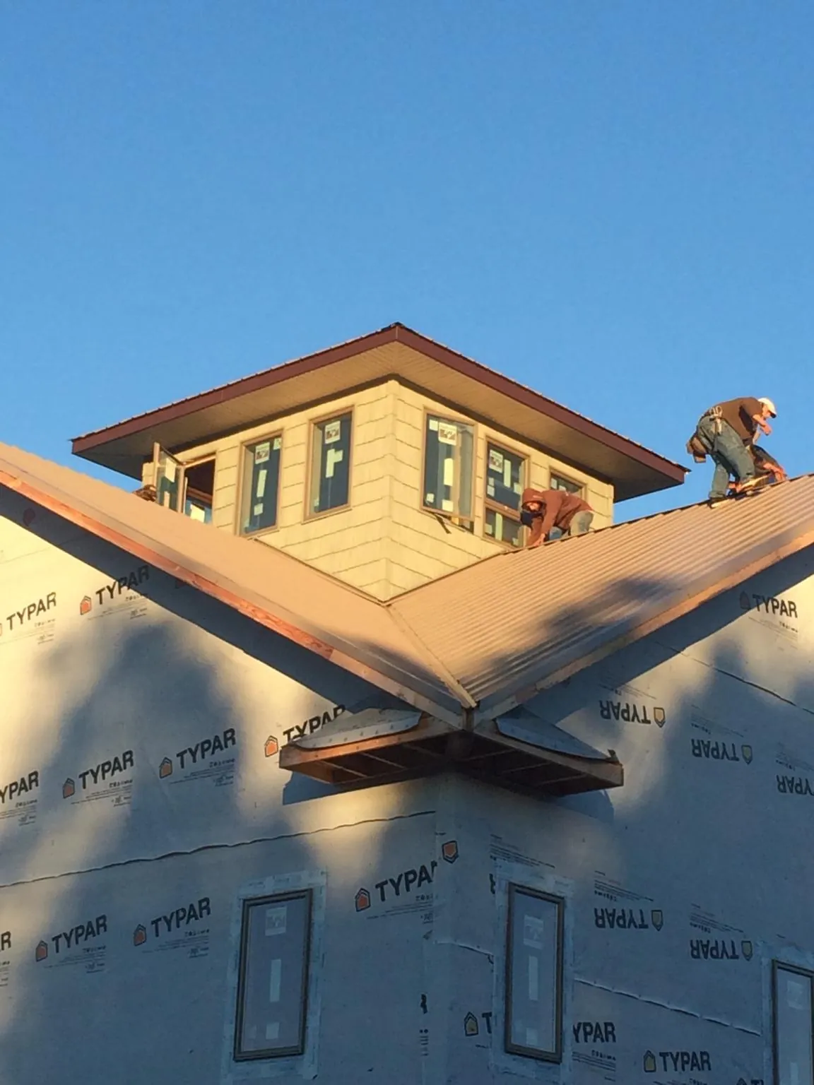 Roofers working around a rooftop cupola on a new metal roof at sunset — Roof Waterproofing in Douglas City by Roofing Brothers